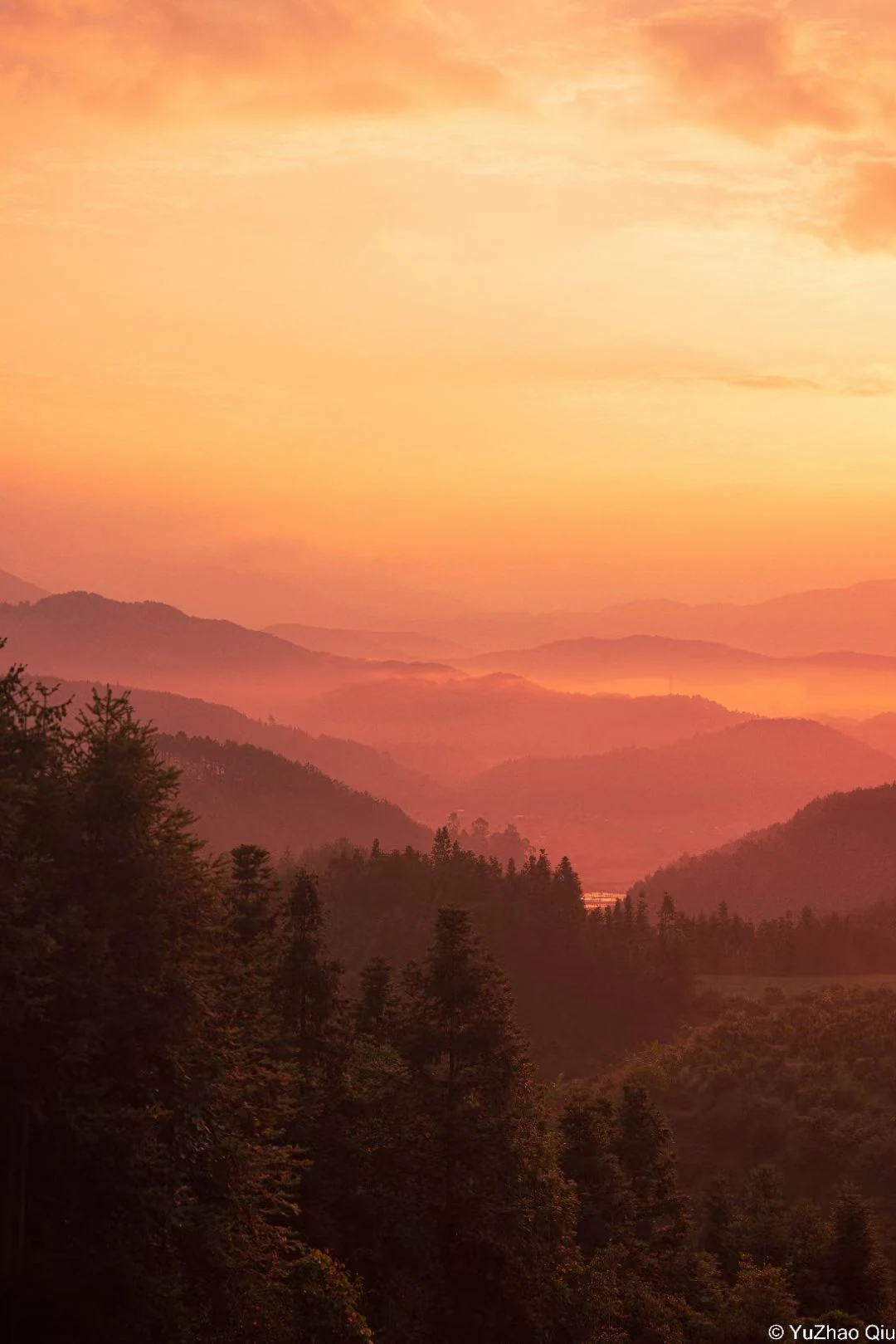 橙红霞光下的重叠山脉与树林